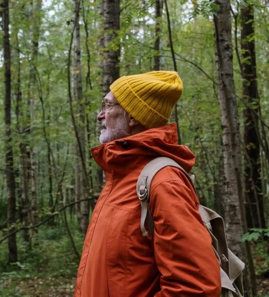 Man in the woods with grey beard, yellow hat and rucksack
